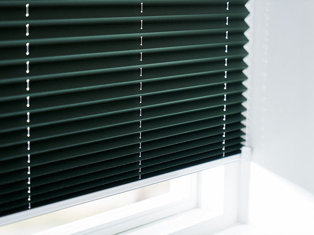 Dyb, mørkegrøn plisségardin skaber stemning og personlighed